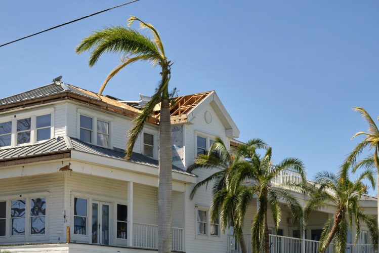 Damaged house roof with missing shingles after hurricane Ian in Florida. Consequences of natural disaster.